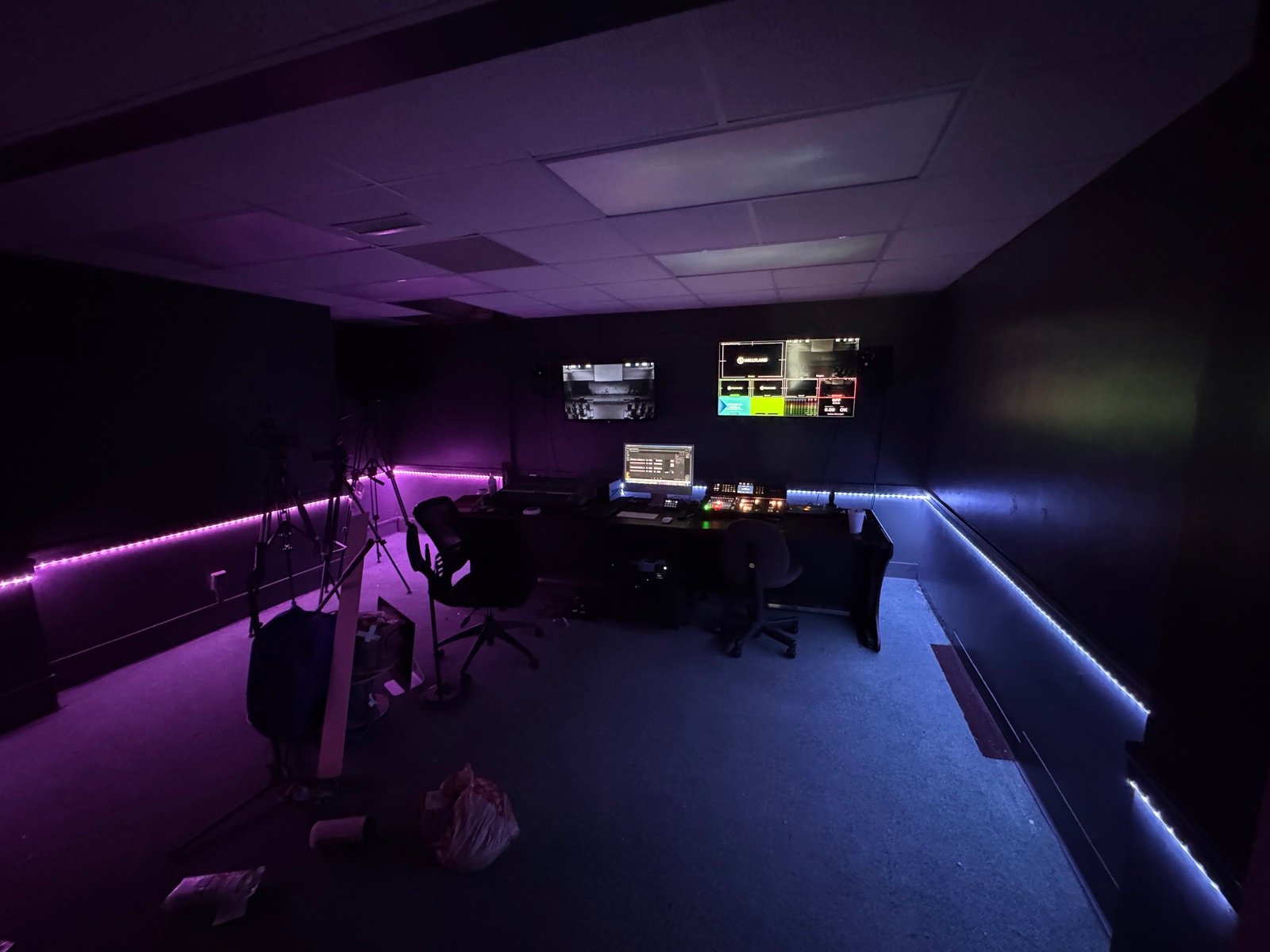 The broadcast room control desk with multiview monitors and switcher, lit by purple and blue LED strips