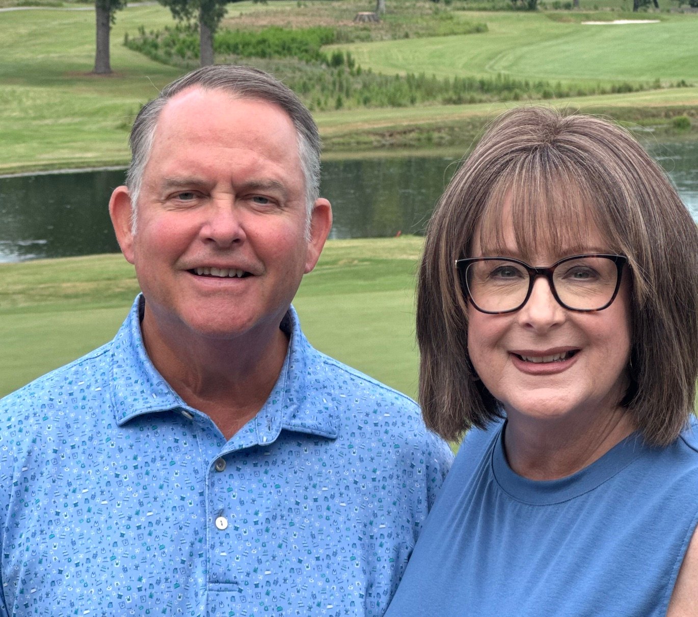 Mark Orr and his wife outdoors on a golf course, smiling at the camera